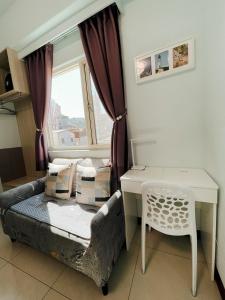 a small room with a bed and a desk and a window at Zucuo Homestay in Nangan