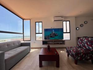 a living room with a couch and a flat screen tv at CONDOMINIO MIRAMAR VISTA AL MAR Playas villamil in Playas