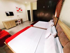 a bedroom with two beds and a couch and a television at The Ambassadors Hotel in Lagos
