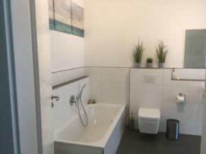 een witte badkamer met een bad en een toilet bij FeWo Pearl 207 am Yachthafen inkl. Tiefgarage in Bremerhaven