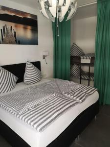 een slaapkamer met een bed met groene gordijnen en een kroonluchter bij FeWo Pearl 207 am Yachthafen inkl. Tiefgarage in Bremerhaven