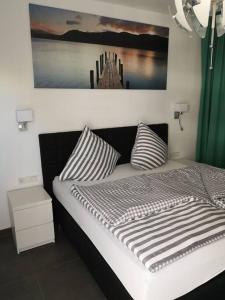 een bed met gestreepte kussens en een foto aan de muur bij FeWo Pearl 207 am Yachthafen inkl. Tiefgarage in Bremerhaven
