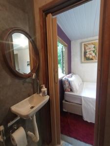 baño con lavabo, espejo y cama en Suítes Caminho das Rosas Experiência na Montanha en Guapimirim