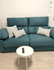 Sofá azul con almohadas y mesa de centro en Apartamentos Aranda - Roble, en Aranda de Duero