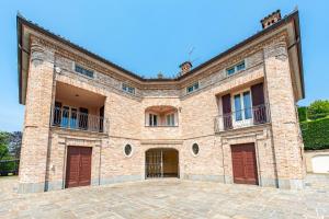 un gran edificio de ladrillo con puertas rojas en Villa Cornelia , entire Villa with private pool, en Corneliano d'Alba