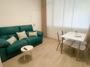 ein Wohnzimmer mit einem grünen Sofa und einem Tisch in der Unterkunft Apartamentos Aranda - Roble in Aranda de Duero