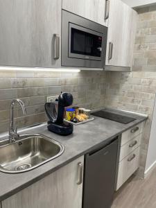 a kitchen with a sink and a microwave at Apartamentos Aranda - Roble in Aranda de Duero
