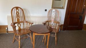 two wooden chairs and a wooden table in a room at Bonkle House in Wishaw