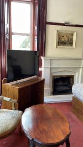 een woonkamer met een tv en een open haard bij Bonkle House in Wishaw
