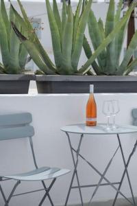 uma mesa com uma garrafa, uma cadeira e uma planta em Luxury Apartment Center of Mykonos Town - Sleeps 4 em Míconos