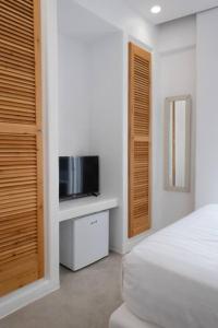 um quarto branco com uma cama e uma televisão em Luxury Apartment Center of Mykonos Town - Sleeps 4 em Míconos