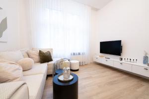 a white living room with a white couch and a tv at Modern 5min Wenceslas Square APT in Prague