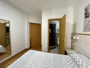 Habitación blanca con cama y espejo en Montero Sestao Bilbao en Trapagaran