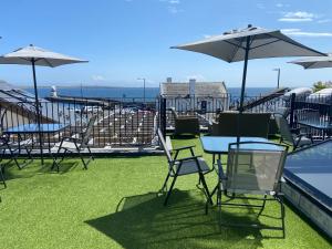 een groep stoelen en tafels met parasols naast een zwembad bij Halvard Apartments at Castletown in Castletown