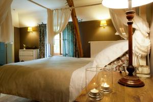 ein Schlafzimmer mit einem Bett und einem Tisch mit einer Lampe in der Unterkunft Ferme de l'Abbaye St-Feuillien in Roeulx