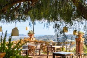 un grupo de mesas y sillas bajo un árbol en Boutique Hotel Finca el Tossal - Adults Only, en Bolulla