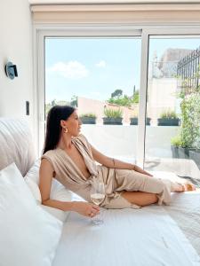 una mujer sentada en una cama con una copa de vino en Step One | Luxury Suites right in the heart of Acropolis next to metro station en Athens
