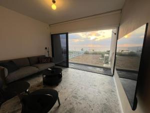 sala de estar con sofá y ventana grande en דירת גן על הים בנהריה, en Nahariyya