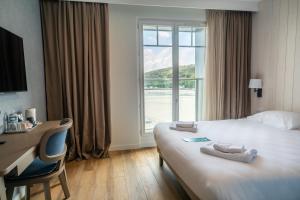 a hotel room with a bed and a desk and a window at Hôtel de la Baie in Crozon