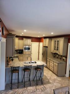 a kitchen with white cabinets and a island with bar stools at 5 Bedroom Bethel Maine home in Bethel