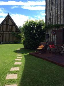 un patio de césped con un edificio, una mesa y una silla en Ancien Relais de Poste, en Collandres-Quincarnon
