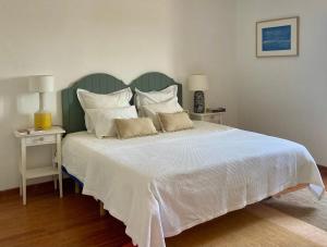 1 dormitorio con 1 cama grande con sábanas y almohadas blancas en Herdade da Burquilheira, en Alcáçovas
