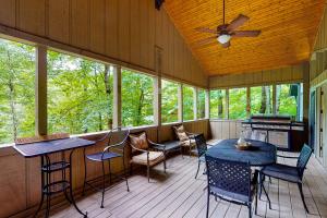 un porche cubierto con mesas, sillas y ventanas en Bear Creek Cabin, en Sapphire