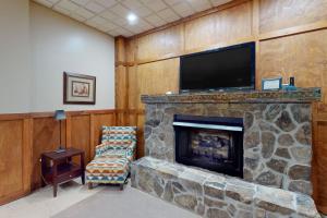 sala de estar con chimenea de piedra y TV de pantalla plana en Bear Creek Cabin, en Sapphire