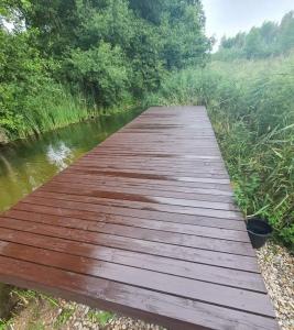 un puente de madera sobre un río con árboles en Domek nad rzeką Rospuda 