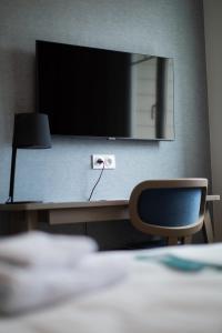 a desk with a monitor and a lamp and a chair at Hôtel de la Baie in Crozon