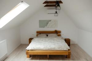 1 dormitorio con cama de madera en una habitación blanca en Guest House Zanoaga, en Prejmer