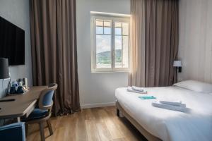 a hotel room with a bed and a desk and a window at Hôtel de la Baie in Crozon