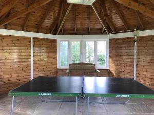 a ping pong table in a room with wooden walls at Liming Lodge - Lakeside Home in the Cotswolds in South Cerney