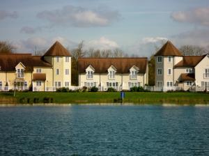 a row of houses next to a body of water at Liming Lodge - Lakeside Home in the Cotswolds in South Cerney