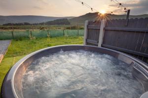 a hot tub in a backyard with the sun setting at OAKWOOD GLAMPING Mourne Mountains in Moyad