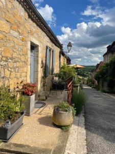 uma casa de pedra com uma mesa e um banco numa rua em Maison de la Combe em Domme