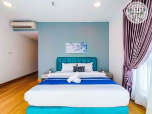 a bedroom with a large bed with blue walls at Teega Suites by JBcity Home in Nusajaya
