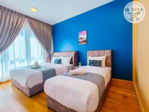 two beds in a room with a blue wall at Teega Suites by JBcity Home in Nusajaya