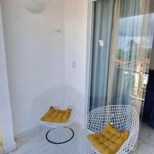 Duas cadeiras brancas com almofadas amarelas numa varanda em Apartamento Novo em Piranhas em Piranhas