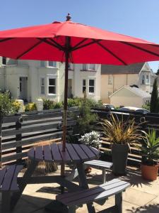 un paraguas rojo sentado en la parte superior de un banco en The St. Leonards Guest House en Shanklin