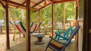 2 Stühle und eine Hängematte auf einer Veranda in der Unterkunft Arrecife Punta Uva - Hospedaje, bar y restaurante - Frente al mar in Punta Uva
