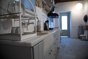 a white kitchen with a sink and a counter at Traditional Village House in Istérnia +31 photos