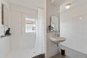Baño blanco con lavabo y espejo en Lemon Suites Hildrizhausen - Ideal für Teams und Monteure, en Hildrizhausen