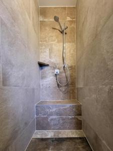 a shower in a bathroom with a stone wall at Komfort Ferienwohnungen Reit im Winkl - Haus Davis in Reit im Winkl