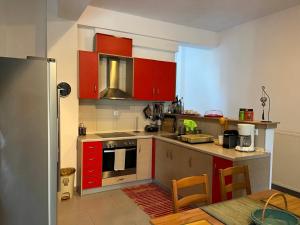 a kitchen with red cabinets and a table in it at Angelo’s Elegant Summer House in Possidi +13 photos