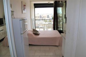 een slaapkamer met een bed en uitzicht op een balkon bij Studio 82, Héliopolis FGH au Village naturiste in Cap d'Agde