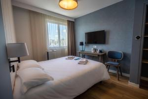 a hotel room with a bed and a television at Hôtel de la Baie in Crozon