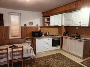 a kitchen with white cabinets and a table and a dining room at La Remus in Moieciu de Jos