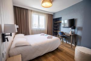 a hotel room with a large bed and a desk at Hôtel de la Baie in Crozon