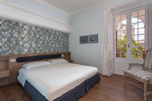 um quarto com uma cama, uma cadeira e uma janela em Borgo Prima Luce em Cuglieri